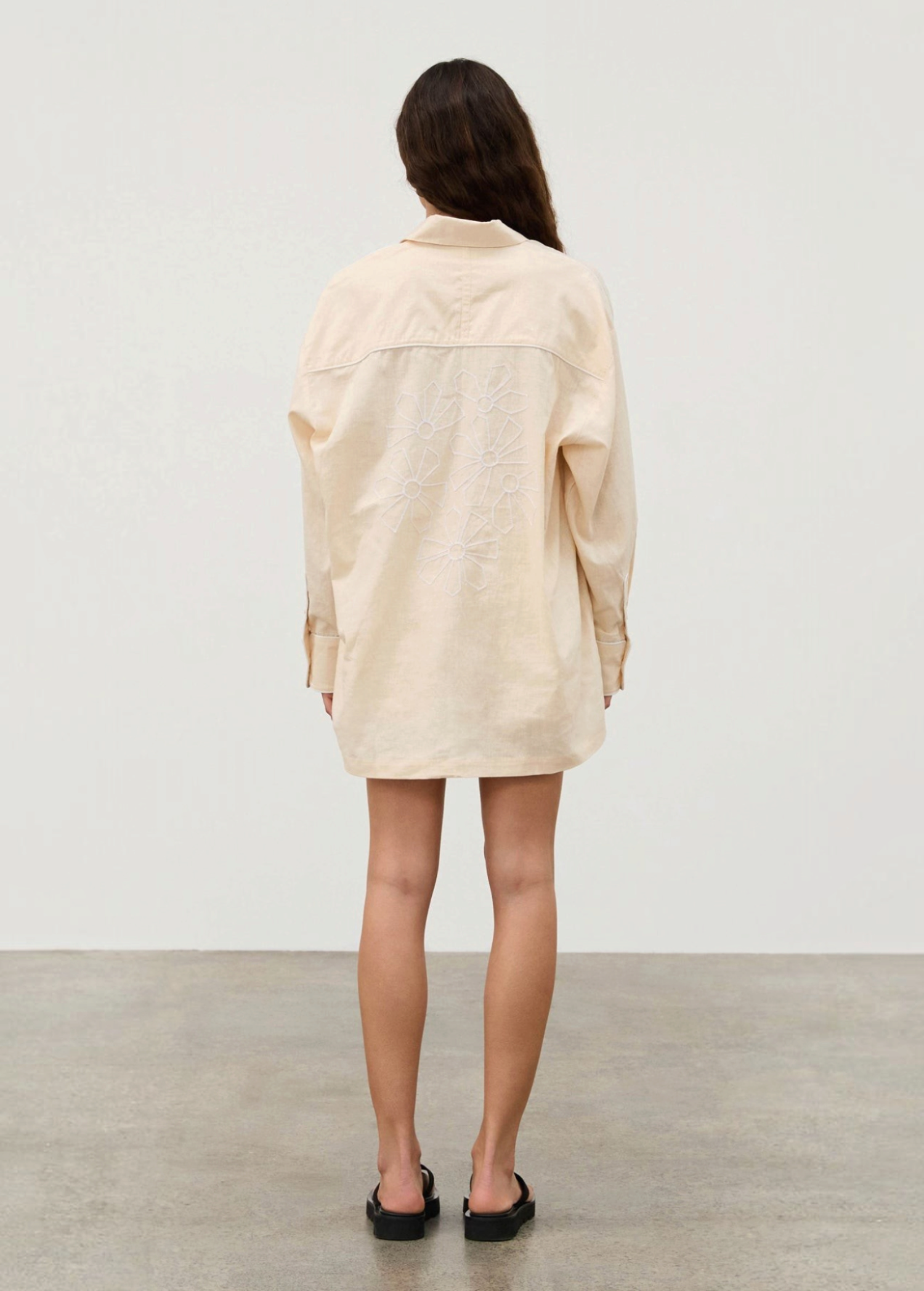 Back view of a person wearing a beige Shea Embroidered Hemp Blend Shirt with geometric floral embroidery on the back.