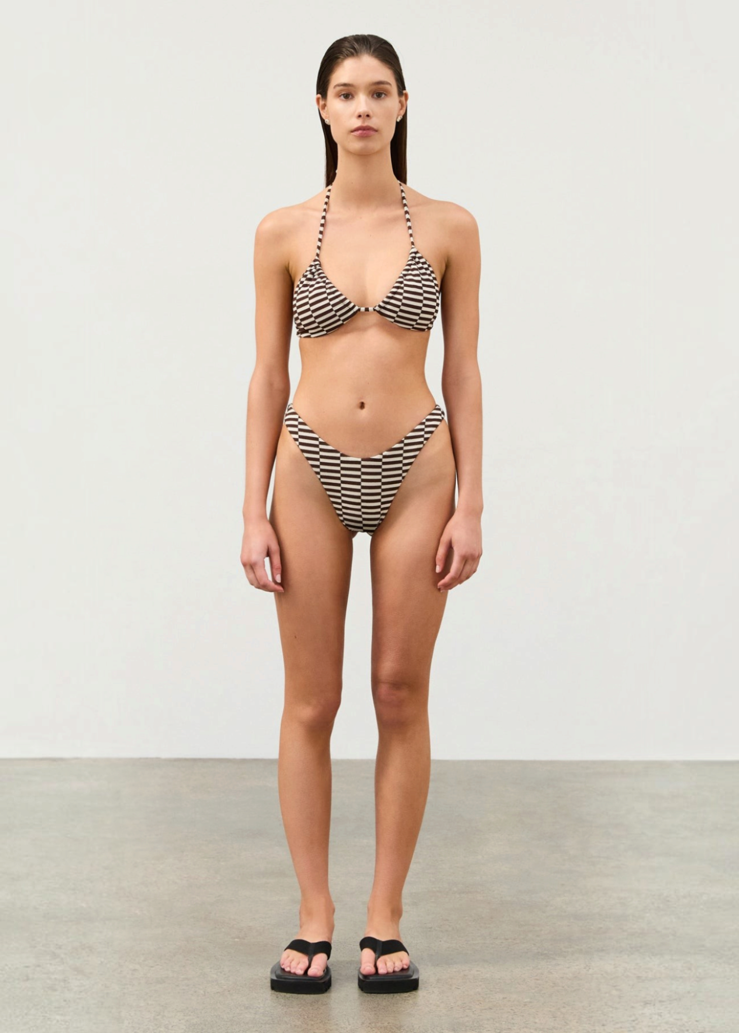 Model wearing KABE SHOP INC cocoa grid textured bikini set with a curved high-cut waist and moderate coverage.