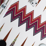 A close-up of the ZigZag Backgammon Board Game, featuring a vibrant acrylic zigzag design with black and white checkers, a doubling cube set to 64, and a white die displaying two dots. The bold zigzag patterns make this board an eye-catching addition to any coffee table.