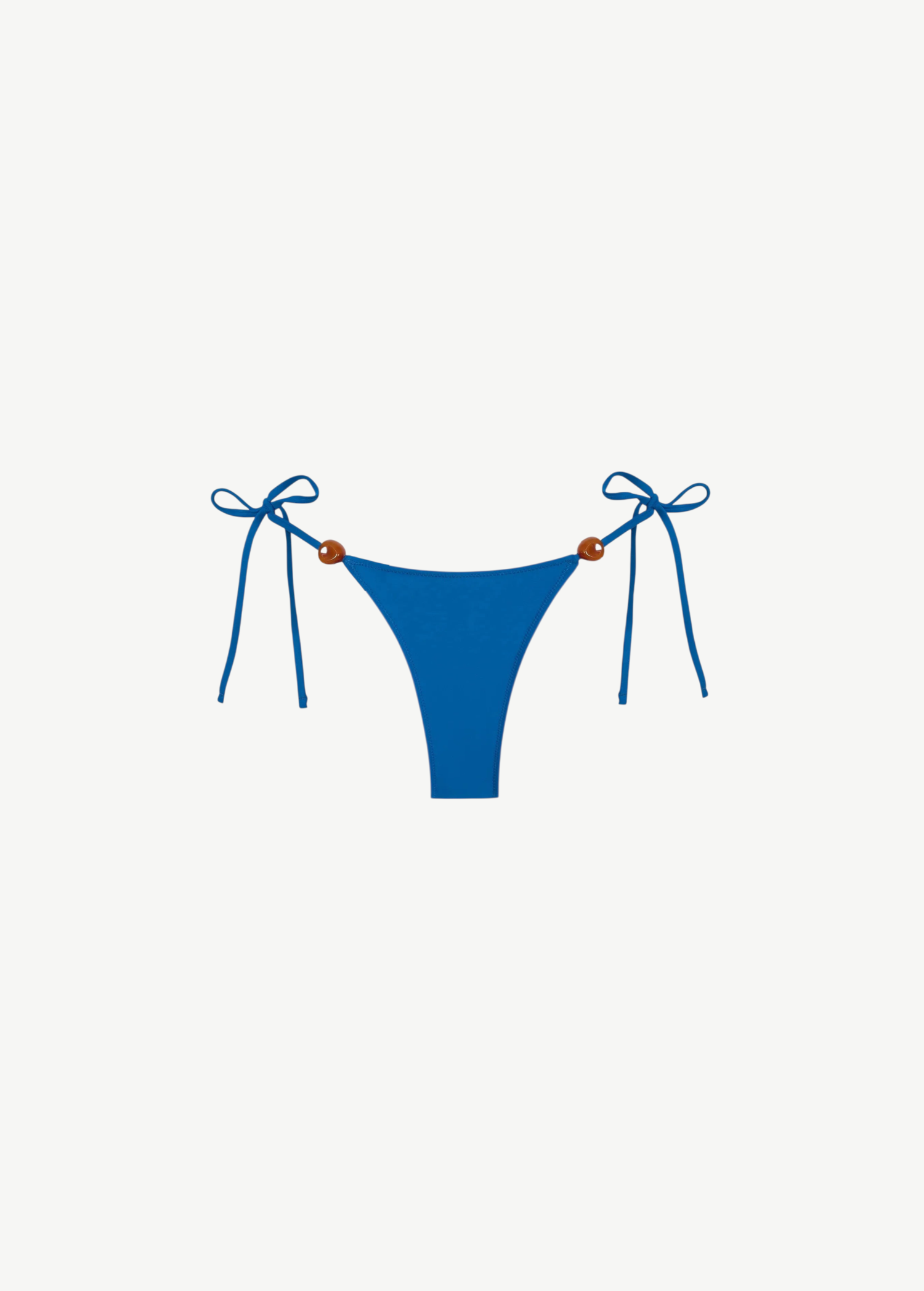 Praia Bottom in blue, crafted from eco-friendly Peach Perfect fabric, features adjustable side tie strings with brown bead accents on each hip. Displayed on a white background, this swimwear combines comfort and style for a flawless fit.