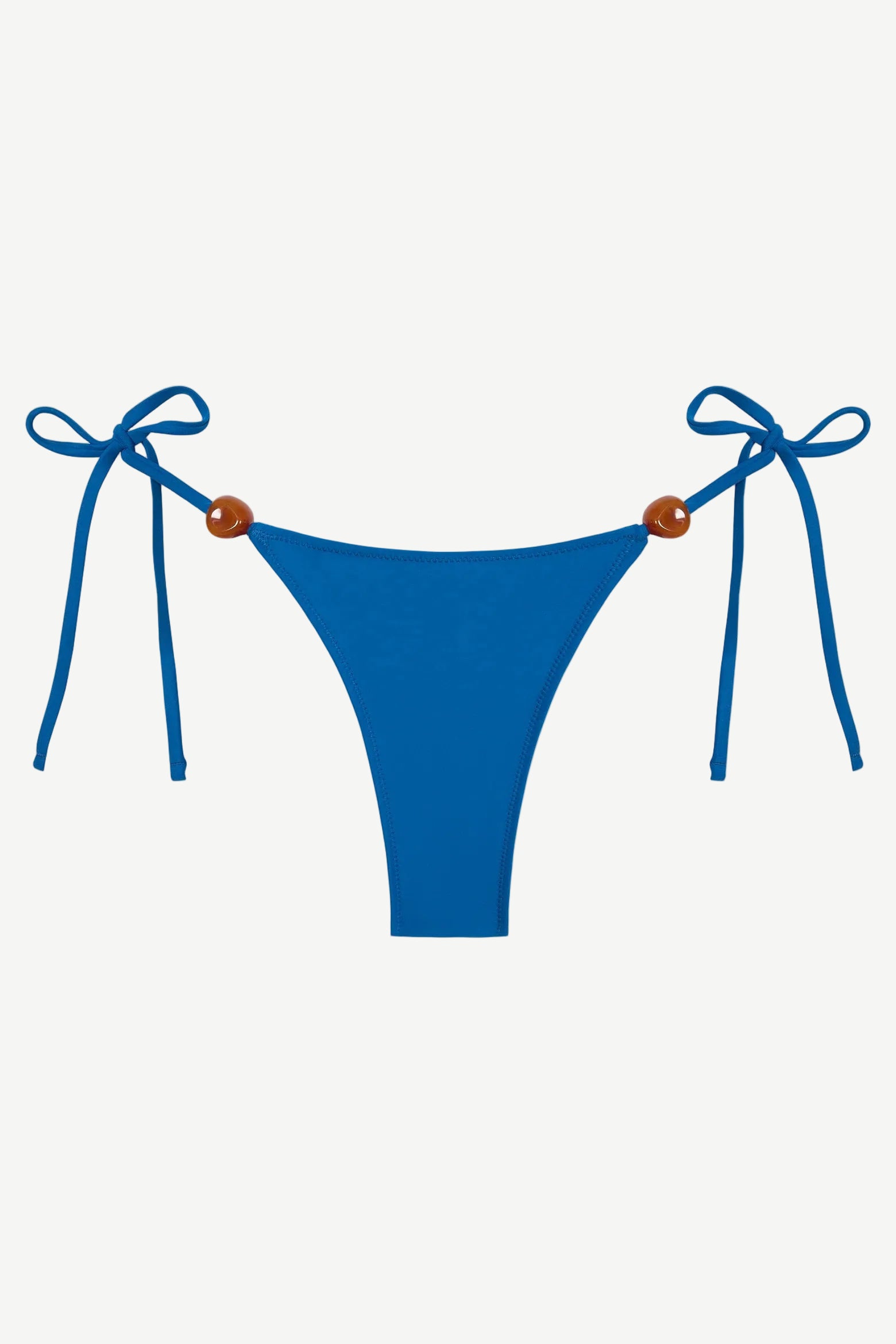 Praia Bottom in blue, crafted from eco-friendly Peach Perfect fabric, features adjustable side tie strings with brown bead accents on each hip. Displayed on a white background, this swimwear combines comfort and style for a flawless fit.