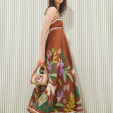 Model wearing a KABE SHOP INC Alfie Twist brown midi sundress with floral print and striped trim against striped wall