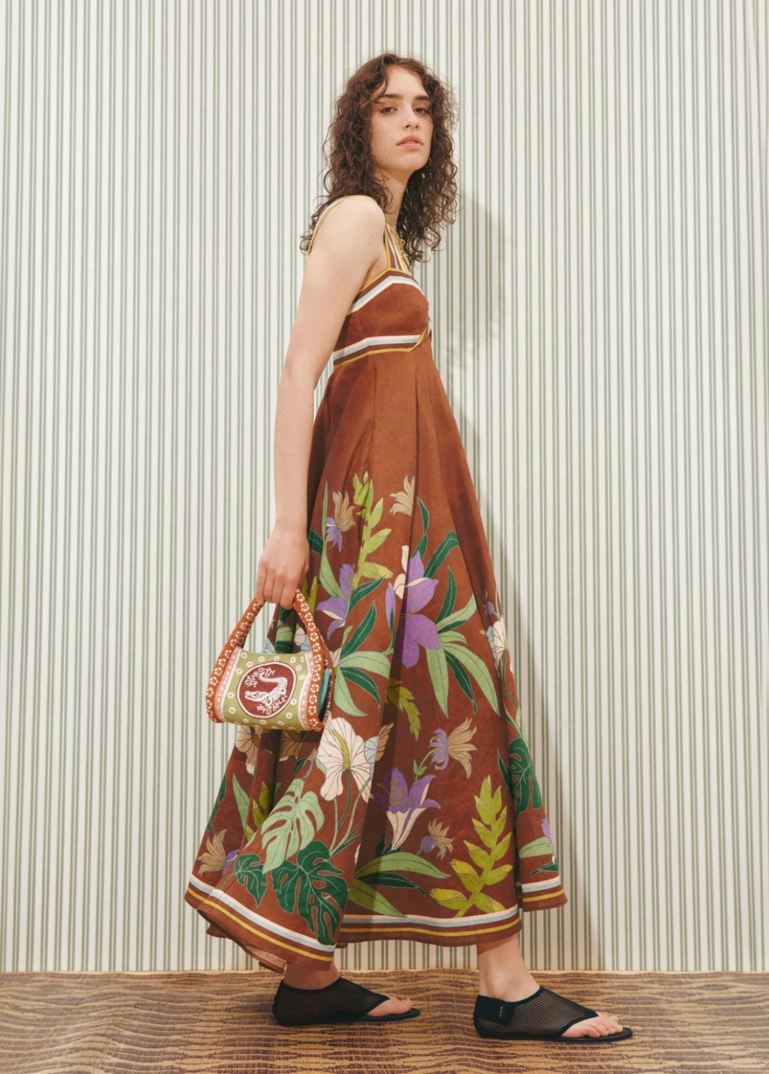 Model wearing a KABE SHOP INC Alfie Twist brown midi sundress with floral print and striped trim against striped wall