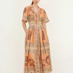 Model wearing KABE SHOP INC Alberta midi shirtdress in orange with a vintage-inspired tropical print and cinched waist.