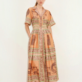Model wearing KABE SHOP INC Alberta midi shirtdress in orange with a vintage-inspired tropical print and cinched waist.