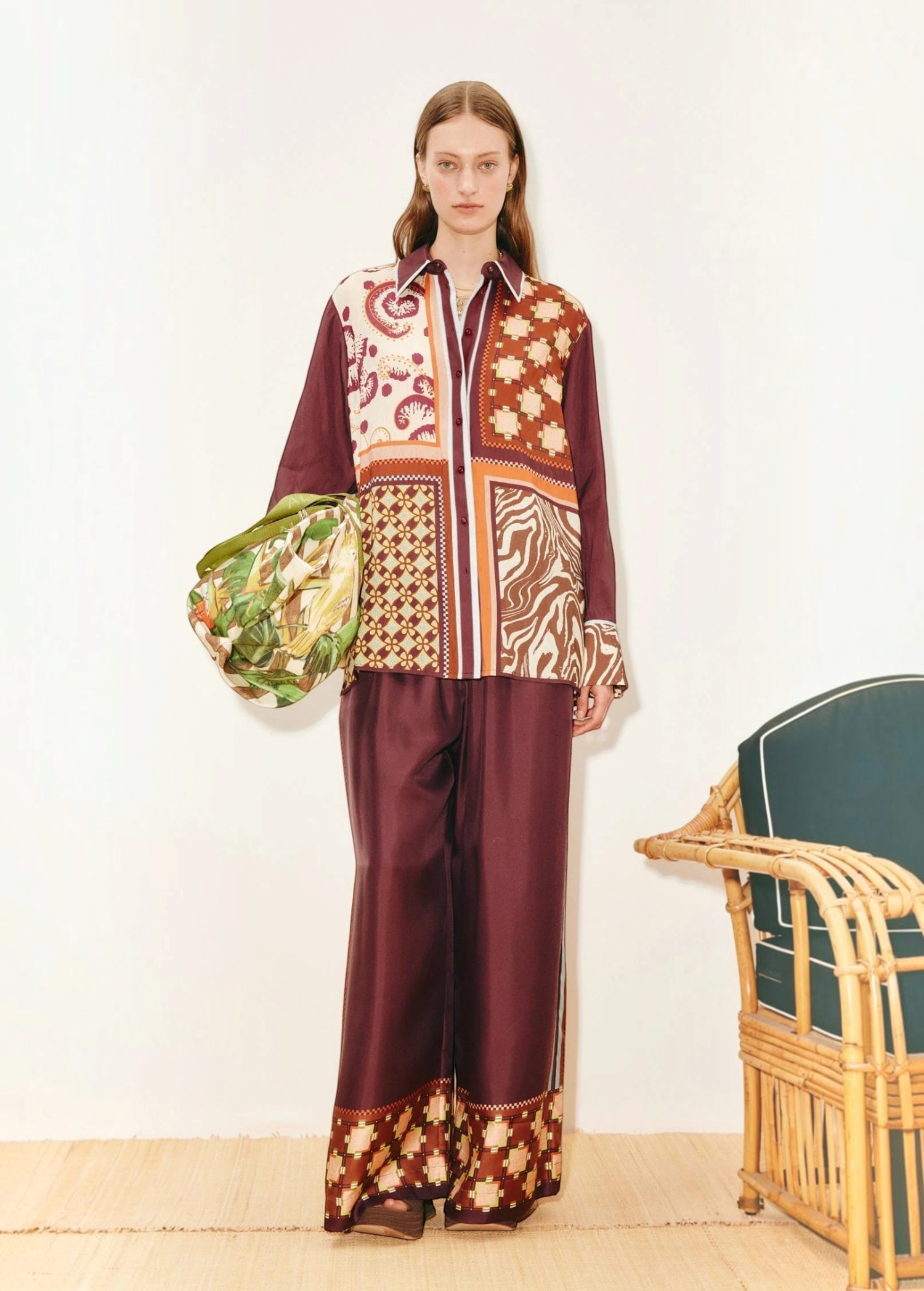 Model wearing KABE SHOP INC Wilson Pants in deep burgundy with a matching patterned shirt and green patterned bag.