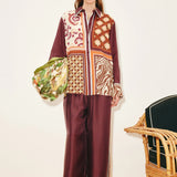 A model wears a Wilson Shirt and matching wide-leg pants in a multicolored patchwork pattern, holding a patterned green bag to create a versatile silhouette.