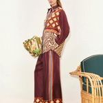A person wears a Wilson Shirt and matching wide-leg trousers, both featuring a mix of geometric, checkered, and zebra print patterns in burgundy, brown, and cream to create a versatile silhouette.