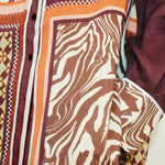 Close-up of the Wilson Shirt, a relaxed, button-down featuring a patchwork design of brown and white zebra print, geometric patterns, and solid dark panels.