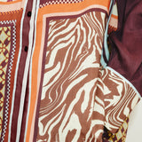 Close-up of the Wilson Shirt, a relaxed, button-down featuring a patchwork design of brown and white zebra print, geometric patterns, and solid dark panels.