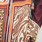 Close-up of the Wilson Shirt, a relaxed, button-down featuring a patchwork design of brown and white zebra print, geometric patterns, and solid dark panels.