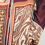 Close-up of the Wilson Shirt, a relaxed, button-down featuring a patchwork design of brown and white zebra print, geometric patterns, and solid dark panels.