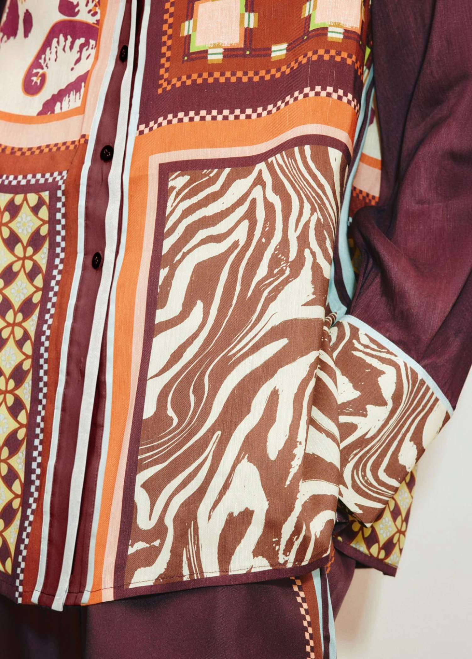 Close-up of the Wilson Shirt, a relaxed, button-down featuring a patchwork design of brown and white zebra print, geometric patterns, and solid dark panels.
