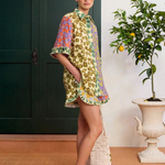Model wearing KABE SHOP INC Patty shorts featuring a vibrant multi-colored floral print and ruffled hem details.