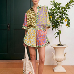 Model wearing KABE SHOP INC Patty Short with a colourful floral print, ruffled hem, and matching button-down shirt.