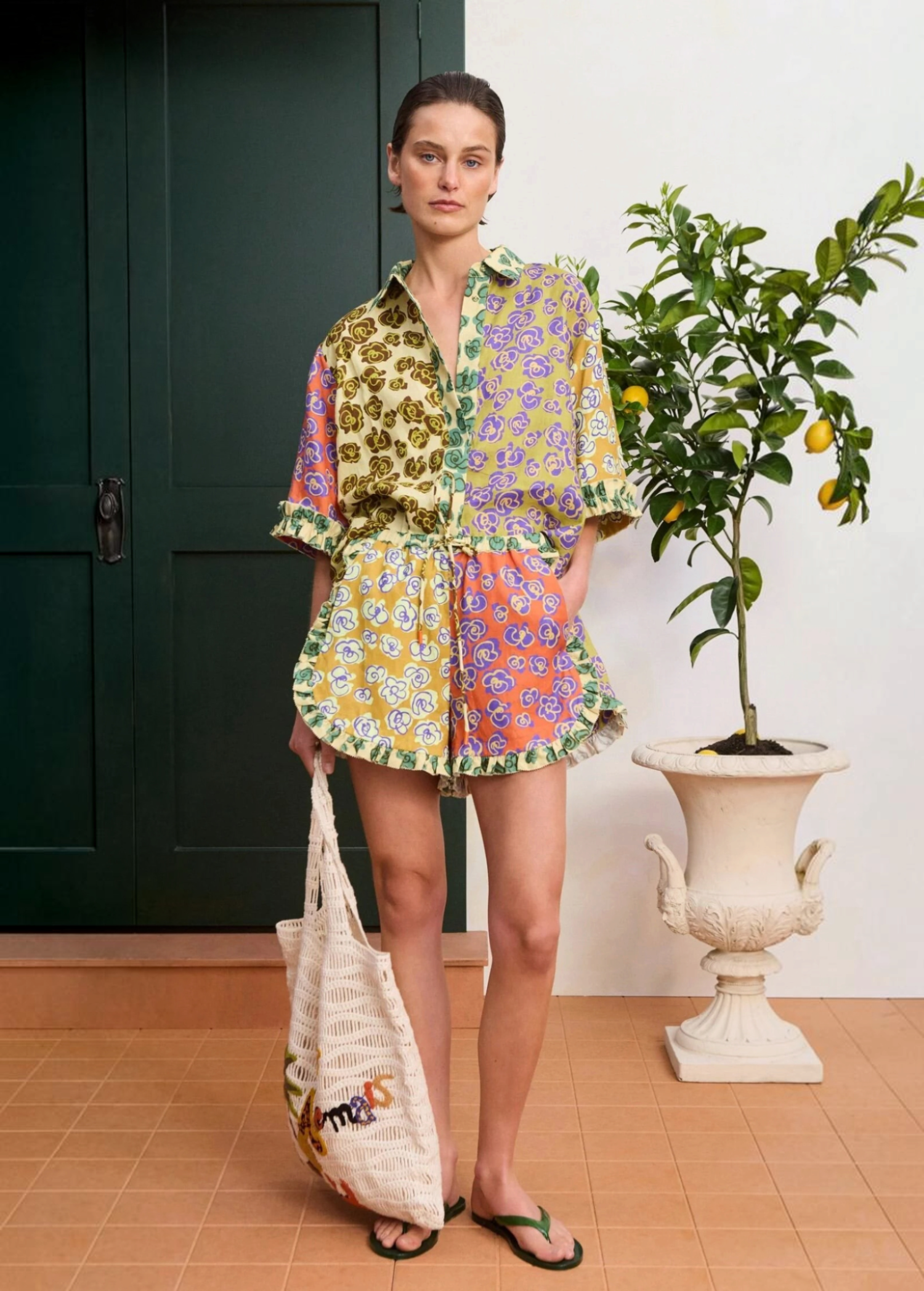 Model wearing KABE SHOP INC Patty Short with a colourful floral print, ruffled hem, and matching button-down shirt.