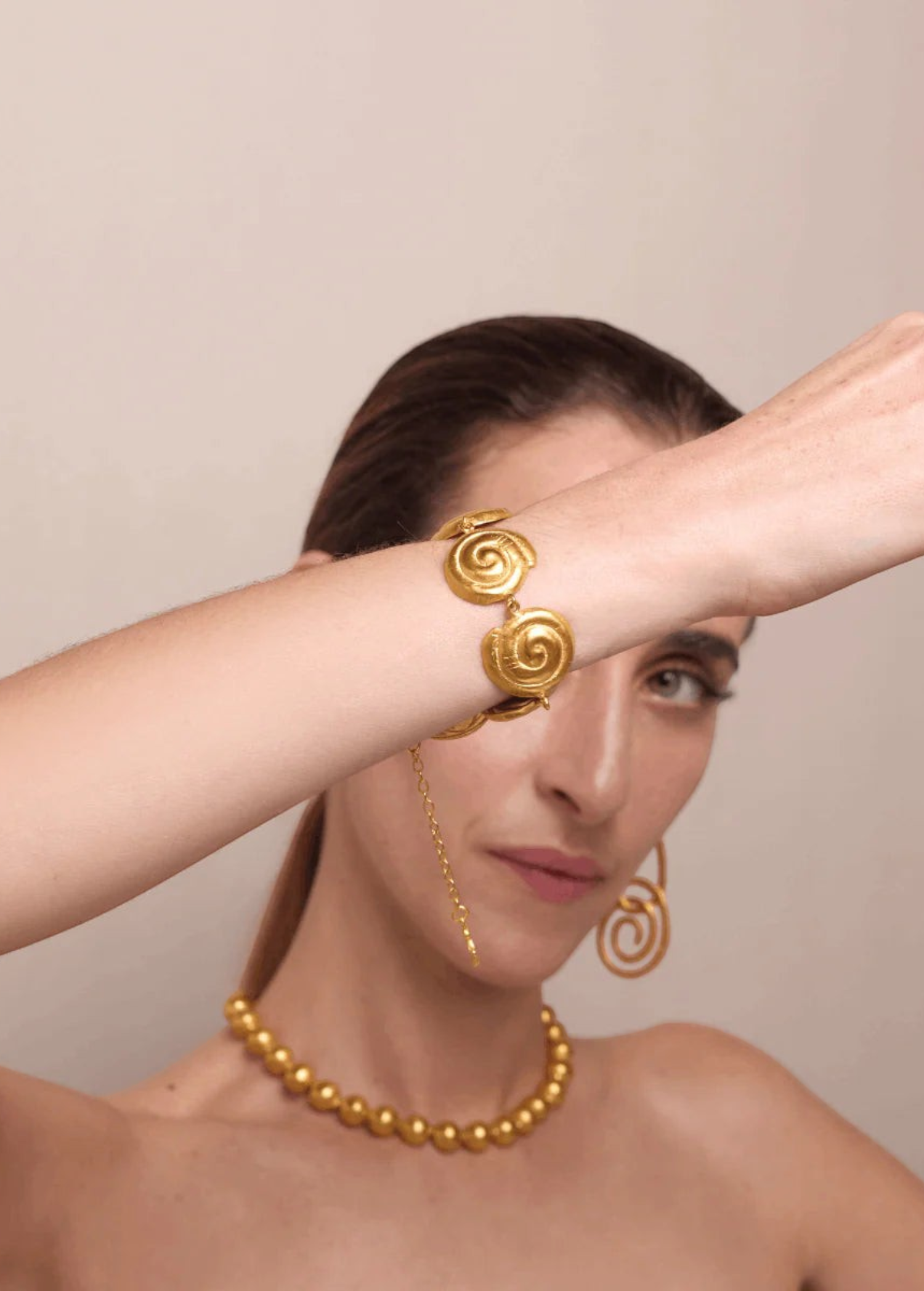 KABE SHOP INC Allinmi bracelet featuring gold spiral Tairona-inspired links worn on a model's wrist
