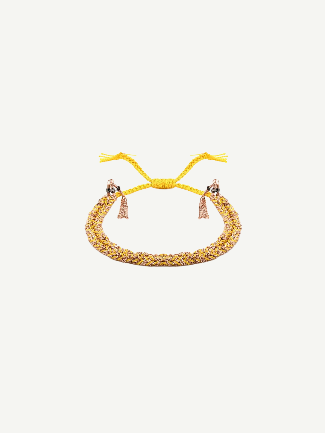 Introducing the N° 183 Braided Bracelet—an elegant piece crafted from yellow and rose gold threads, featuring two delicate dangling tassels and an adjustable closure. Its subtle yellow gold finish is beautifully showcased against a pristine white background.