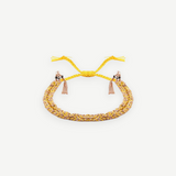 Introducing the N° 183 Braided Bracelet—an elegant piece crafted from yellow and rose gold threads, featuring two delicate dangling tassels and an adjustable closure. Its subtle yellow gold finish is beautifully showcased against a pristine white background.