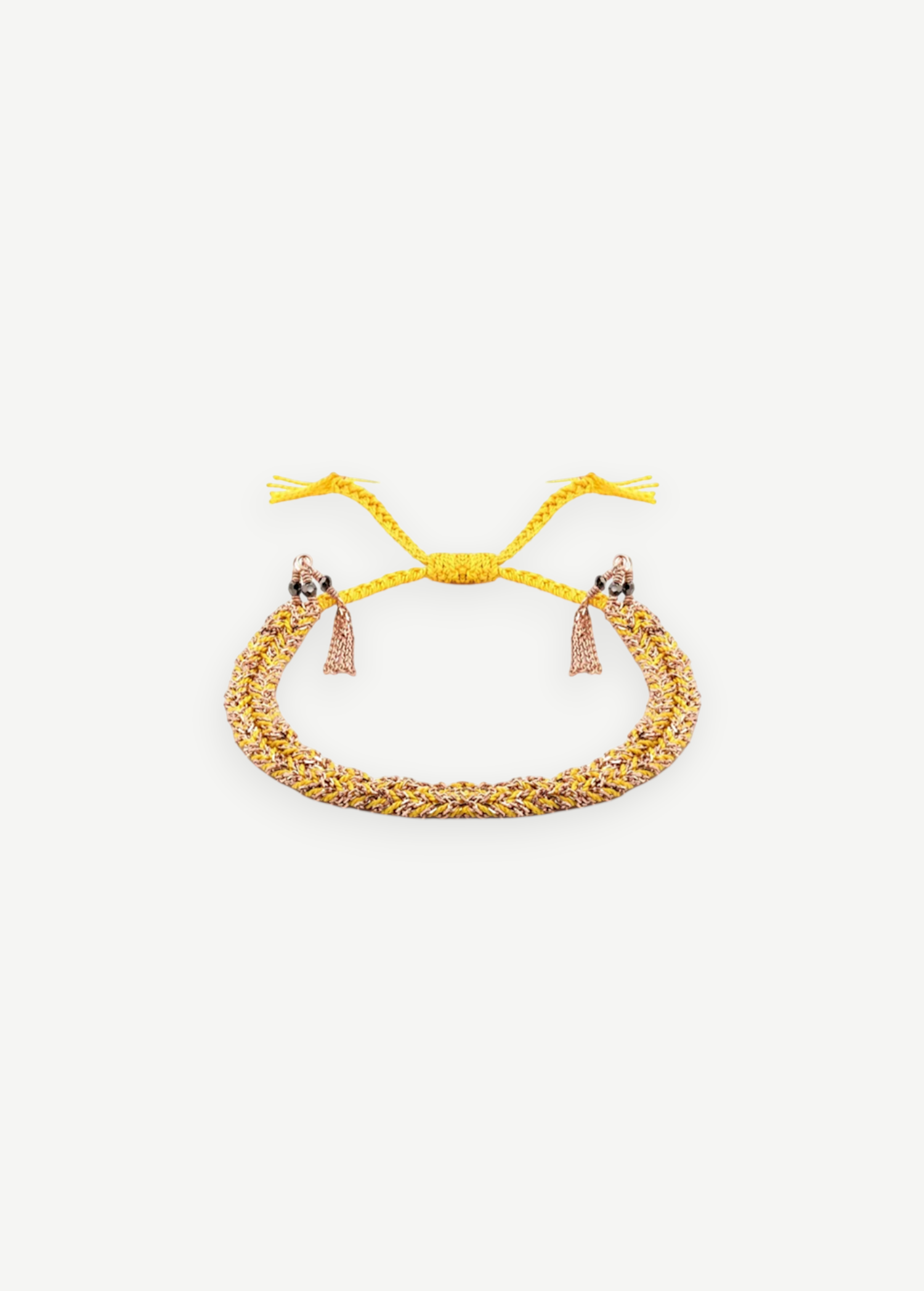 Introducing the N° 183 Braided Bracelet—an elegant piece crafted from yellow and rose gold threads, featuring two delicate dangling tassels and an adjustable closure. Its subtle yellow gold finish is beautifully showcased against a pristine white background.