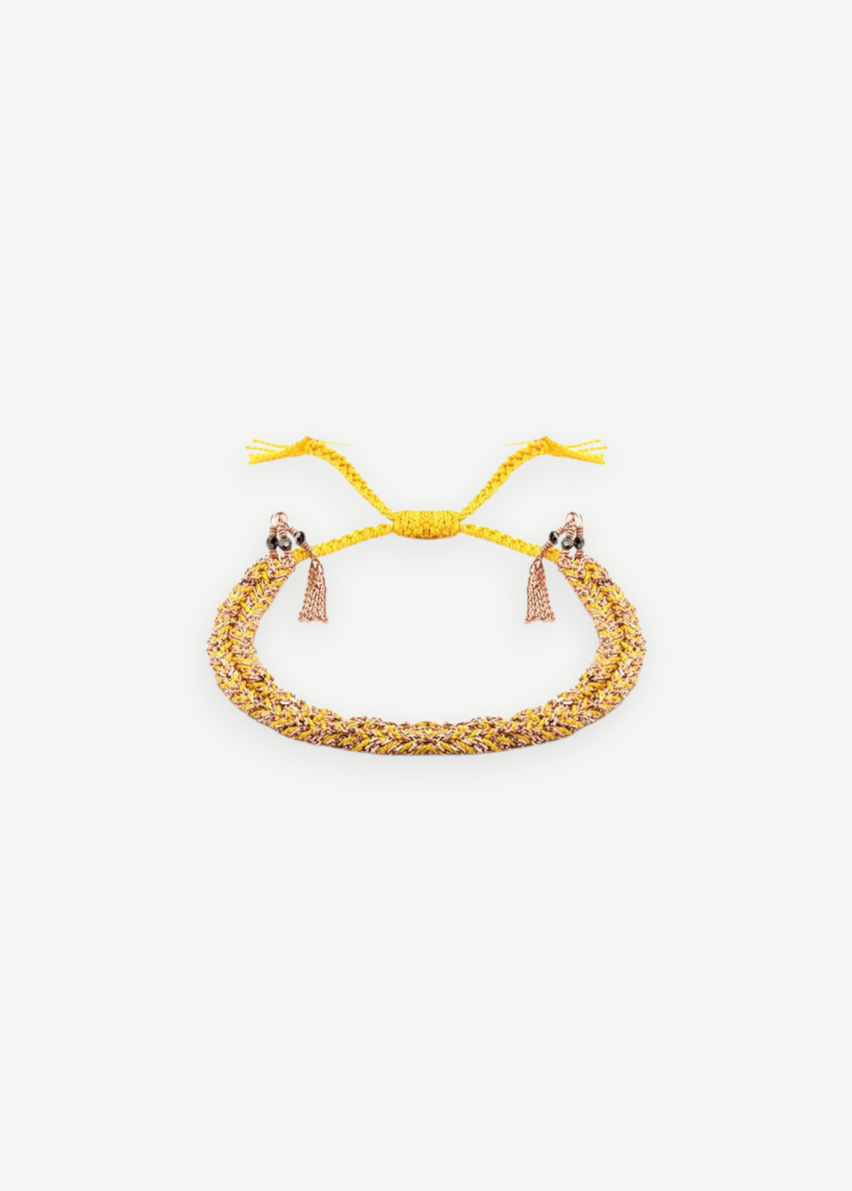 Introducing the N° 183 Braided Bracelet—an elegant piece crafted from yellow and rose gold threads, featuring two delicate dangling tassels and an adjustable closure. Its subtle yellow gold finish is beautifully showcased against a pristine white background.