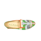 The Anzu Moccasin is a hand-embroidered shoe in green, orange, and cream with intricate patterns and “Meher Kakalia” inscribed on the insole, shown from above against a white background.