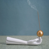 KABE SHOP INC Atlas porcelain incense holder featuring a white hand sculpture balancing a gold sphere with incense