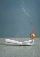 KABE SHOP INC Atlas porcelain incense holder featuring a white hand sculpture balancing a gold sphere with incense