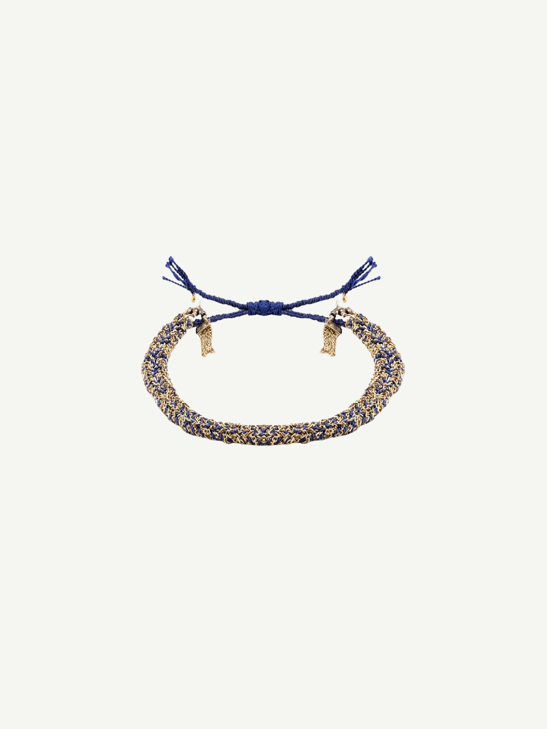The N° 183 Braided Bracelet, crafted with intertwined blue and gold threads, showcases adjustable blue tassel ends and a subtle yellow gold finish, elegantly displayed on a plain white background.