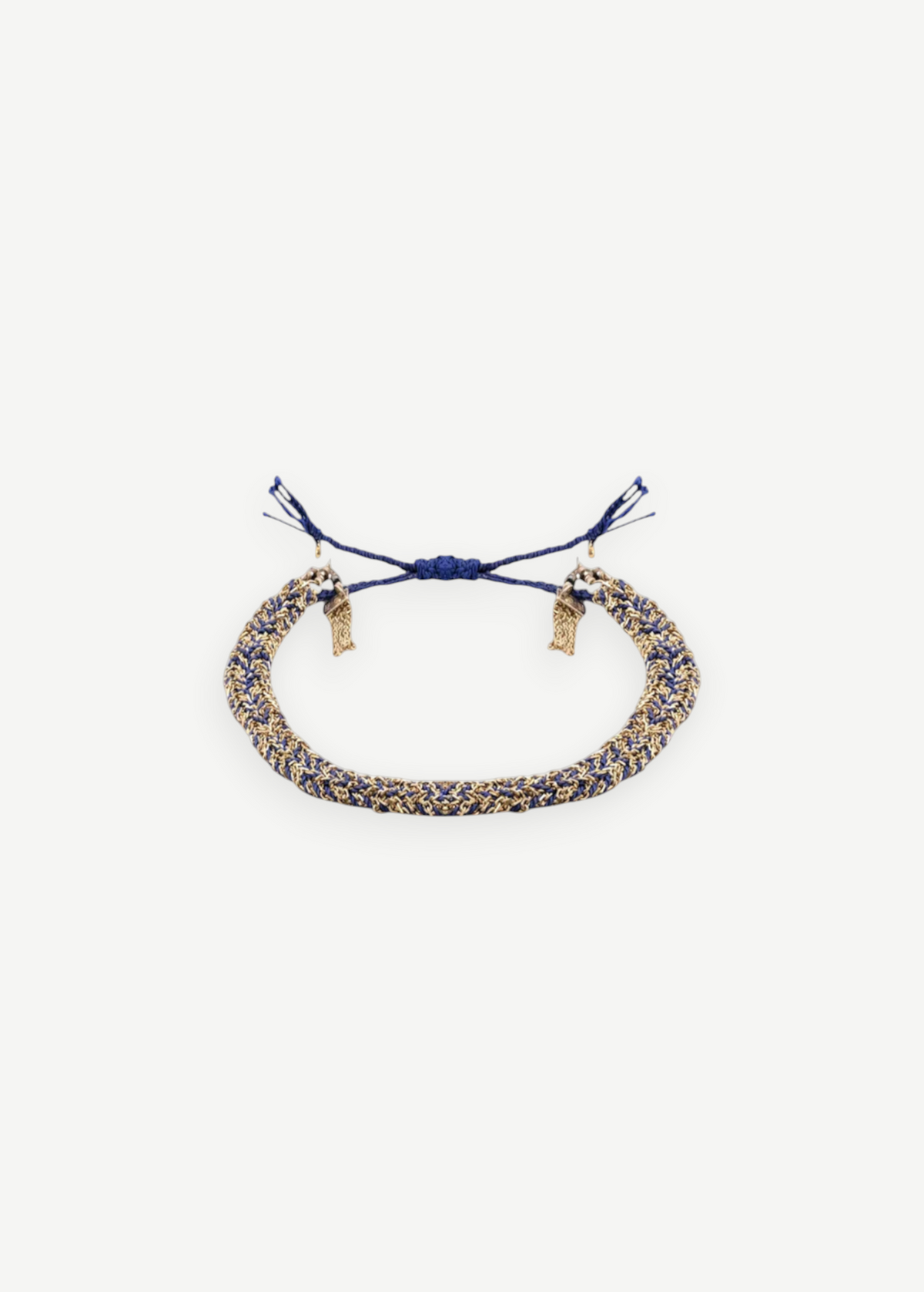 The N° 183 Braided Bracelet, crafted with intertwined blue and gold threads, showcases adjustable blue tassel ends and a subtle yellow gold finish, elegantly displayed on a plain white background.