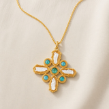 KABE SHOP INC Croix Baroque pendant necklace featuring a gold cross with white baroque pearls and turquoise stones.
