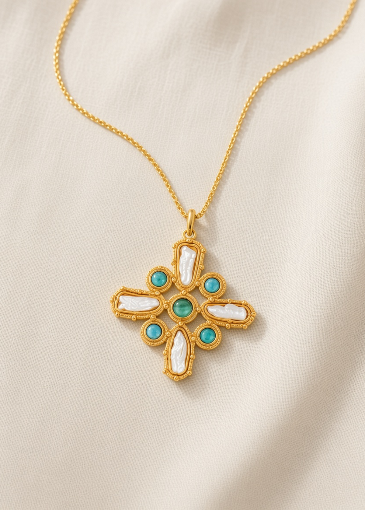 KABE SHOP INC Croix Baroque pendant necklace featuring a gold cross with white baroque pearls and turquoise stones.