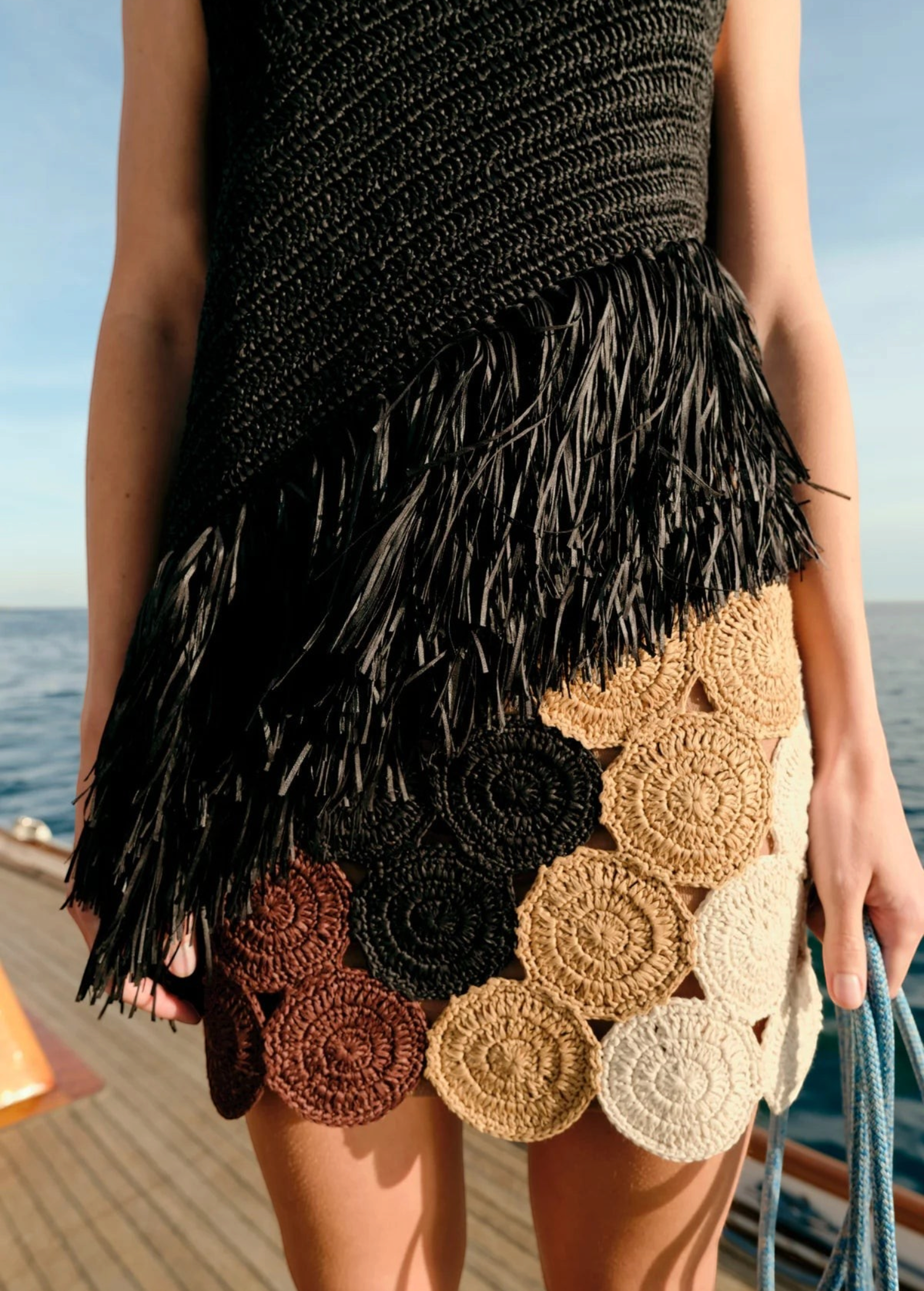 KABE SHOP INC Beep Beep mini skirt featuring hand-knit crochet circular motifs in earth tones on a boat deck
