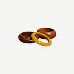 KABE SHOP INC set of three sculptural bangles featuring natural wood and smooth yellow resin in a modern design.