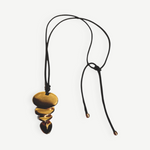 KABE SHOP INC gold sculptural pendant necklace on a long black cord with adjustable knot detail