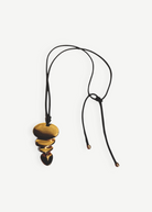 KABE SHOP INC gold sculptural pendant necklace on a long black cord with adjustable knot detail