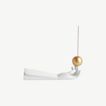 KABE SHOP INC Atlas porcelain incense holder featuring a white hand sculpture balancing a gold sphere with incense