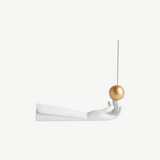 KABE SHOP INC Atlas porcelain incense holder featuring a white hand sculpture balancing a gold sphere with incense