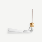 KABE SHOP INC Atlas porcelain incense holder featuring a white hand sculpture balancing a gold sphere with incense
