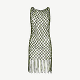 The Castaway Dress is a sleeveless macrame tunic dress crafted from green and black knotted netting with large diamond-shaped openings and long beaded fringe at the hem, handmade in Peru.
