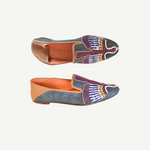 Two Anzu Moccasins featuring colorful, intricate beadwork and tan leather accents are displayed against a white background—one viewed from the top and one from the side. These hand-embroidered leather moccasins highlight vibrant craftsmanship and timeless style.