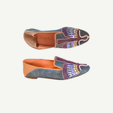Two Anzu Moccasins featuring colorful, intricate beadwork and tan leather accents are displayed against a white background—one viewed from the top and one from the side. These hand-embroidered leather moccasins highlight vibrant craftsmanship and timeless style.
