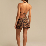KABE SHOP INC Ciclone wrap skirt in a leopard print pattern, worn as a beach cover-up over a matching bikini.