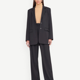 Model wearing KABE SHOP INC Luisa Pant in black with a matching blazer and beige turtleneck for a tailored look.
