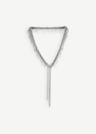The Lariat Necklace White Bronze is a V-shaped lariat necklace in a sleek silver tone, featuring an adjustable length and long cascading chains draping from the center like a metallic ribbon, shown against a plain white background.