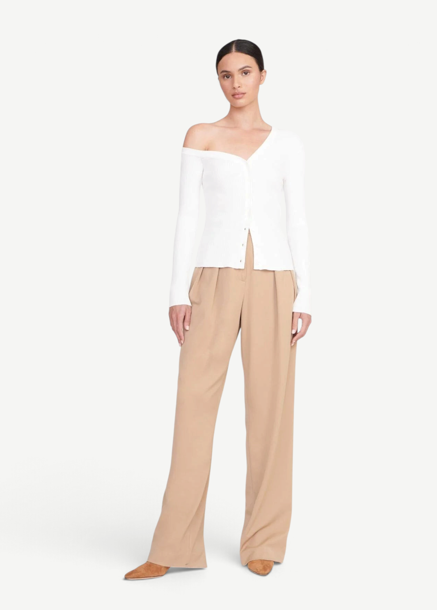 Model wearing a white KABE SHOP INC Craftsman Sweater with an off-the-shoulder neckline and tan trousers
