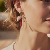KABE SHOP INC shell earrings featuring natural shells, red gemstone drops, and gold accents worn by a woman