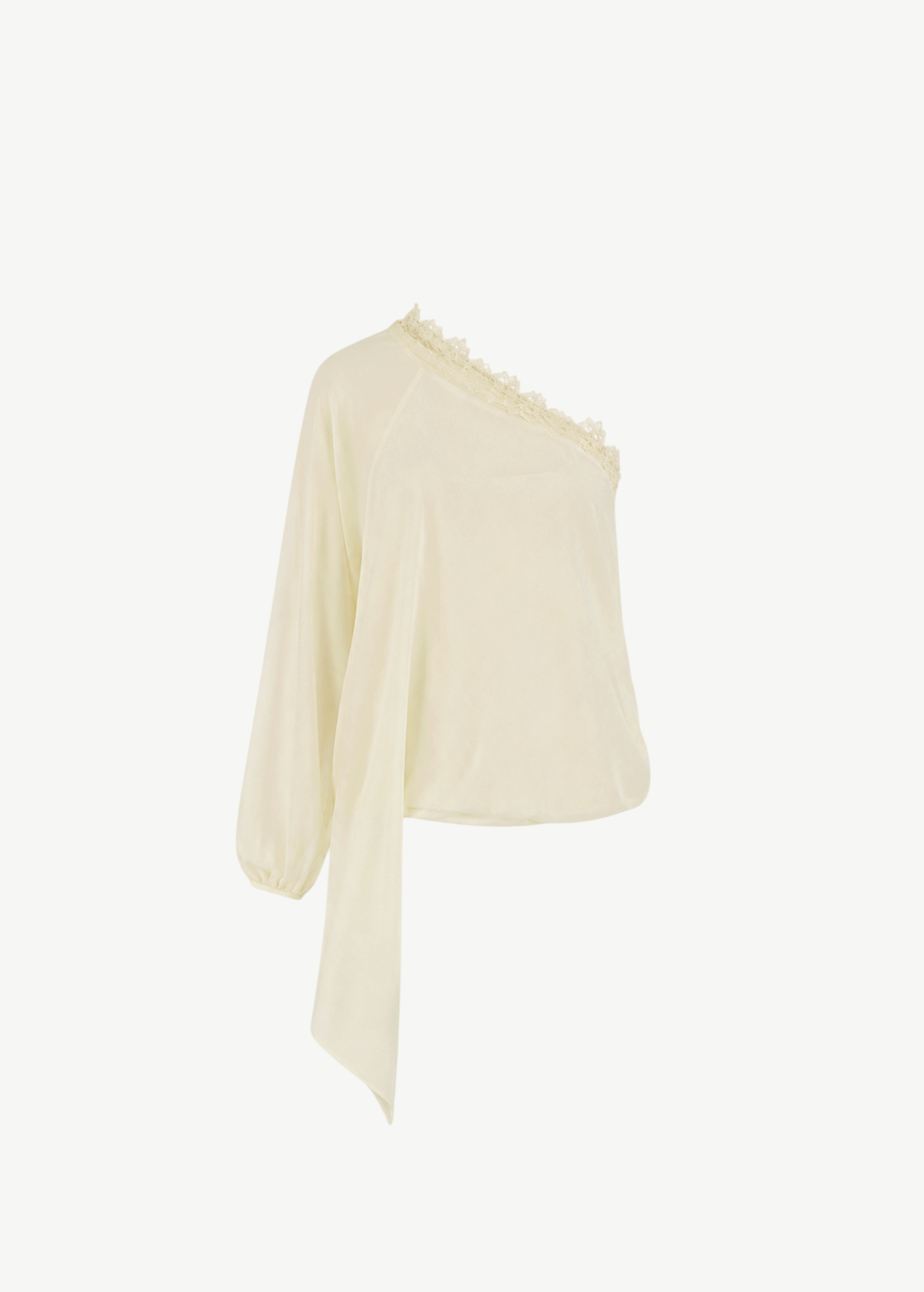 The Elia Top by De La Vali, showcased against a plain white background, features a light yellow hue and is crafted from fluid georgette. This one-shoulder silhouette is detailed with lace trim along the neckline, a single long sleeve, and an asymmetrical draped hem.