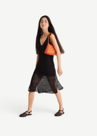 KABE SHOP INC Rosanna Bag in orange handwoven buffalo leather worn over the shoulder by a model in a black dress