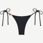 Introducing the Praia Bottom: a black bikini bottom featuring adjustable side ties and two decorative beads—one pink and one beige—on the left. Crafted from recycled polyamide, this minimal, sleek tie-bottom belongs to our eco-friendly swimwear collection, making it an ideal choice for stylish swimmers seeking sustainability.